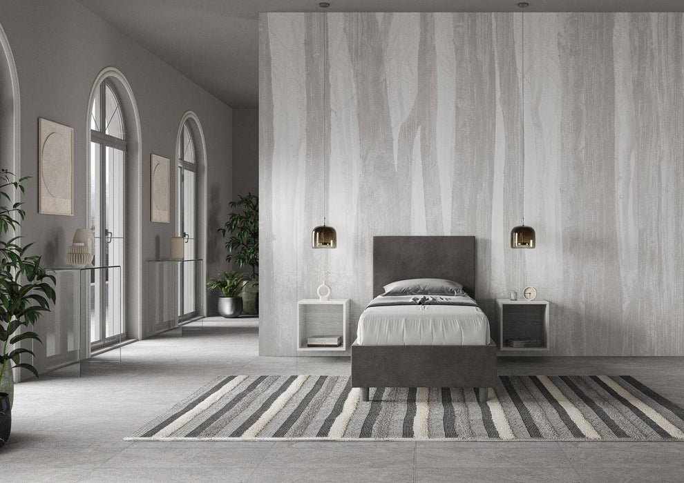 Letto singolo contenitore imbottito 90x200 microfibra Adele grigio scuro in ampio ambiente luminoso. Perfetto per arredare camere minimaliste.