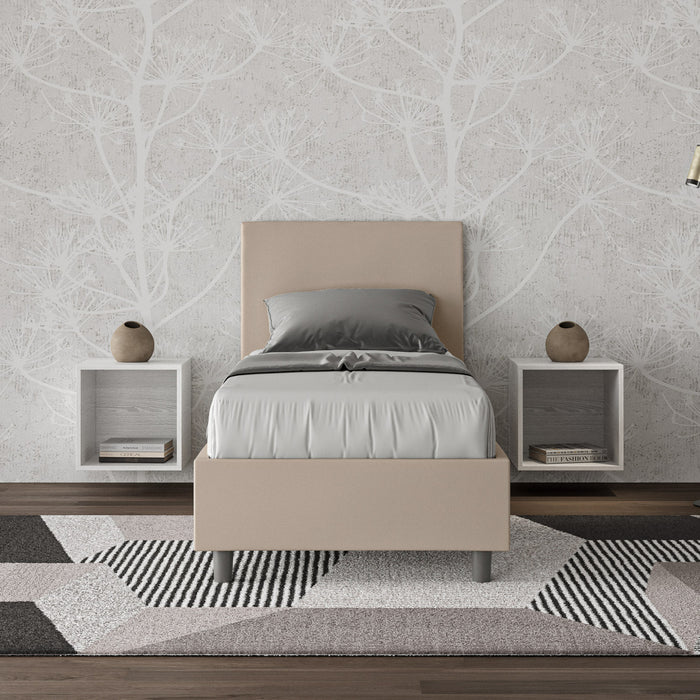 Letto singolo Adele beige in similpelle con testiera imbottita, posizionato in camera con comodini sospesi e tappeto geometrico.