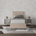 Letto singolo Adele beige in similpelle con testiera imbottita, posizionato in camera con comodini sospesi e tappeto geometrico.
