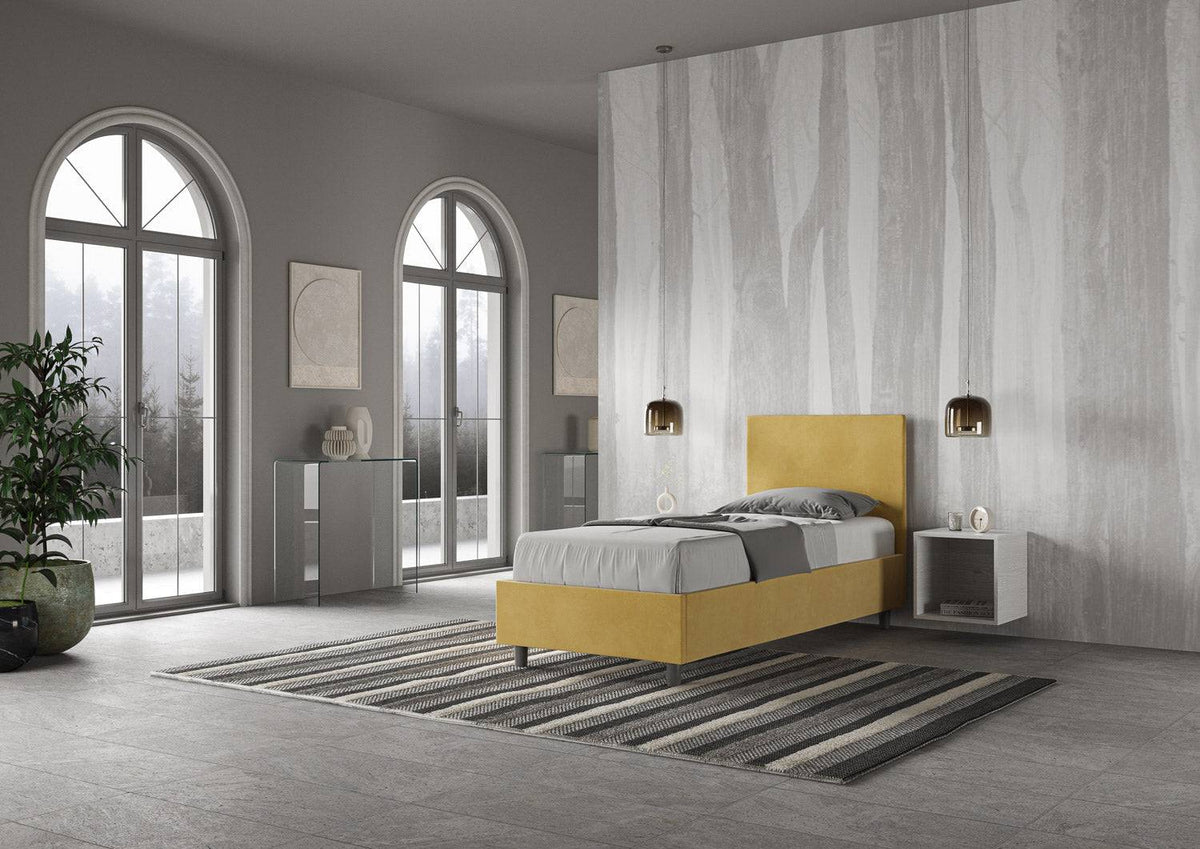 Letto singolo contenitore imbottito 90x200 microfibra Adele giallo senape in ambiente ampio. Design funzionale e accattivante per la zona notte.