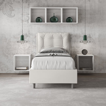 Letto singolo Annalisa bianco in similpelle con testata imbottita, posizionato in una camera elegante con mensole e lampade sospese.