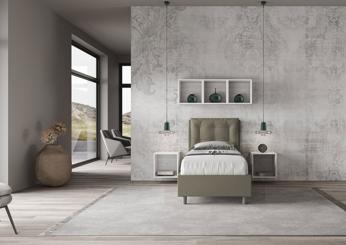 Letto singolo Annalisa grigio in similpelle, inserito in una camera luminosa con decorazioni moderne e ampie finestre panoramiche.