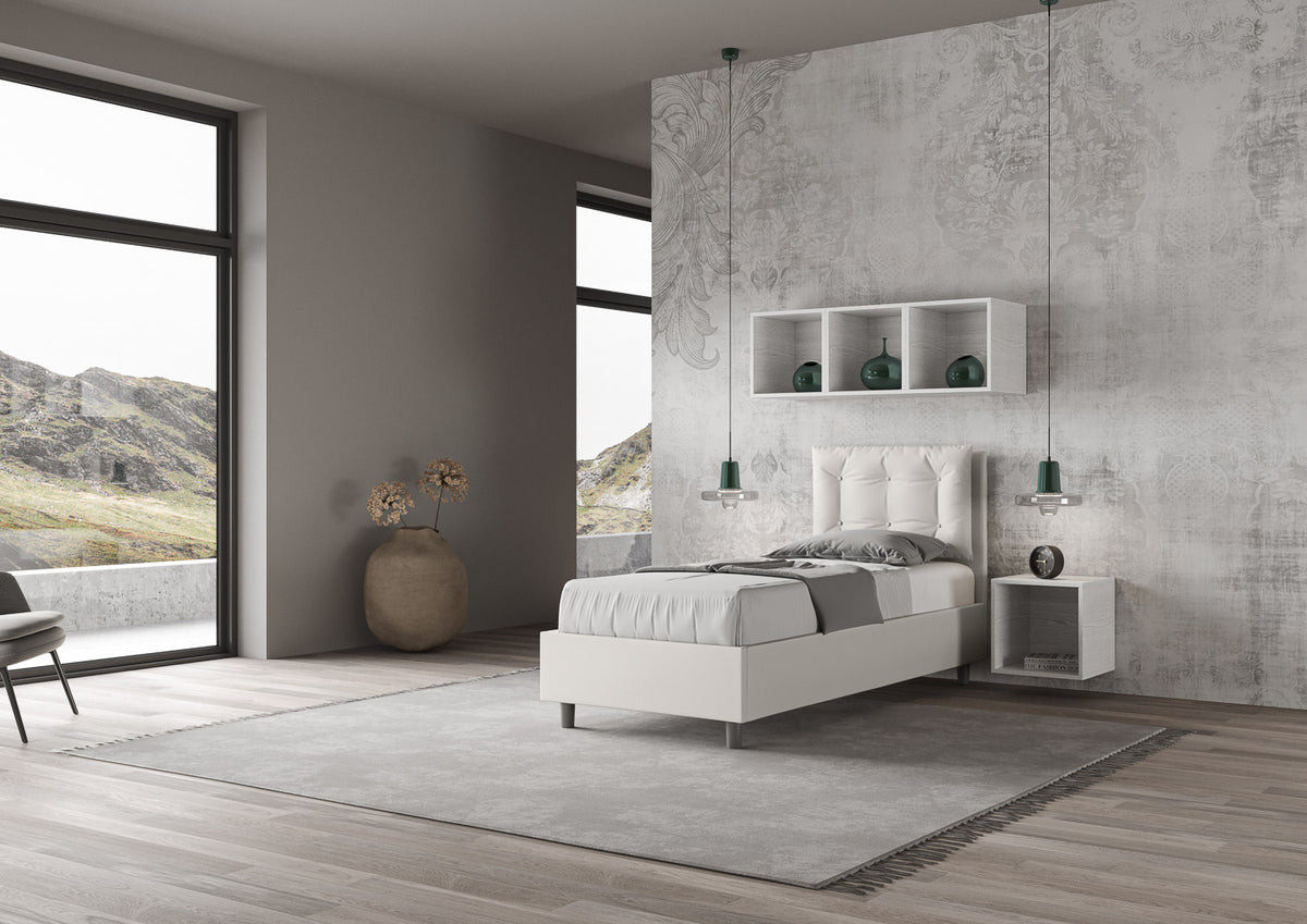 Letto singolo Annalisa bianco in similpelle con testata imbottita, collocato in una stanza luminosa con vista panoramica.