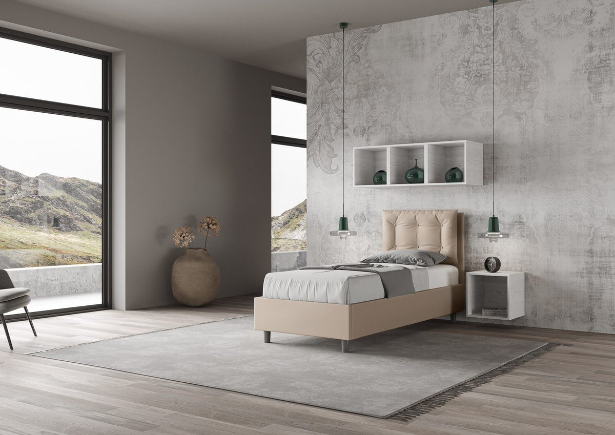 Letto singolo Annalisa beige in similpelle con testata imbottita, collocato in una stanza luminosa con vista panoramica.