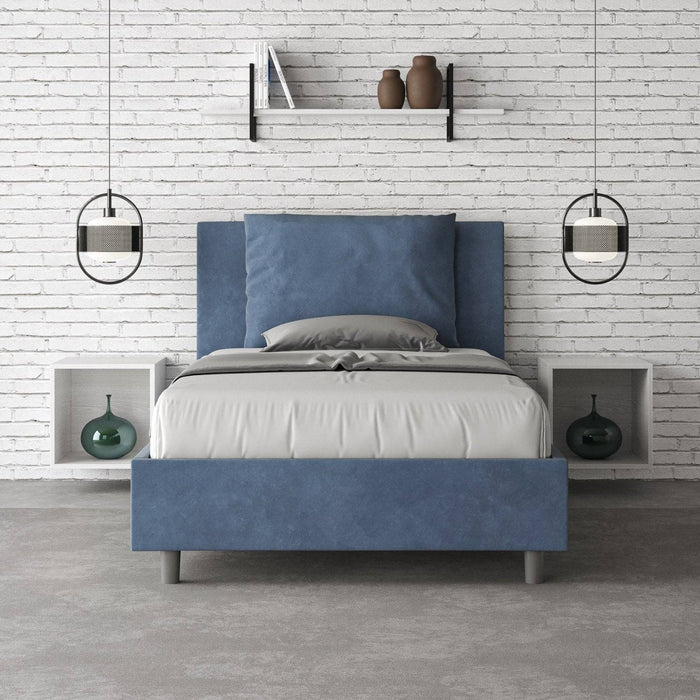 Letto singolo Antea blu navy con contenitore, in una camera minimalista con parete in mattoni bianchi e arredi sospesi.