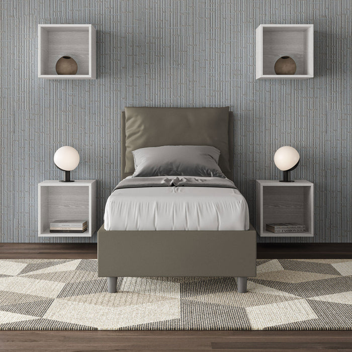 Letto singolo Antea grigio in similpelle con testata imbottita, collocato in una camera moderna con parete grigia e mobili sospesi.