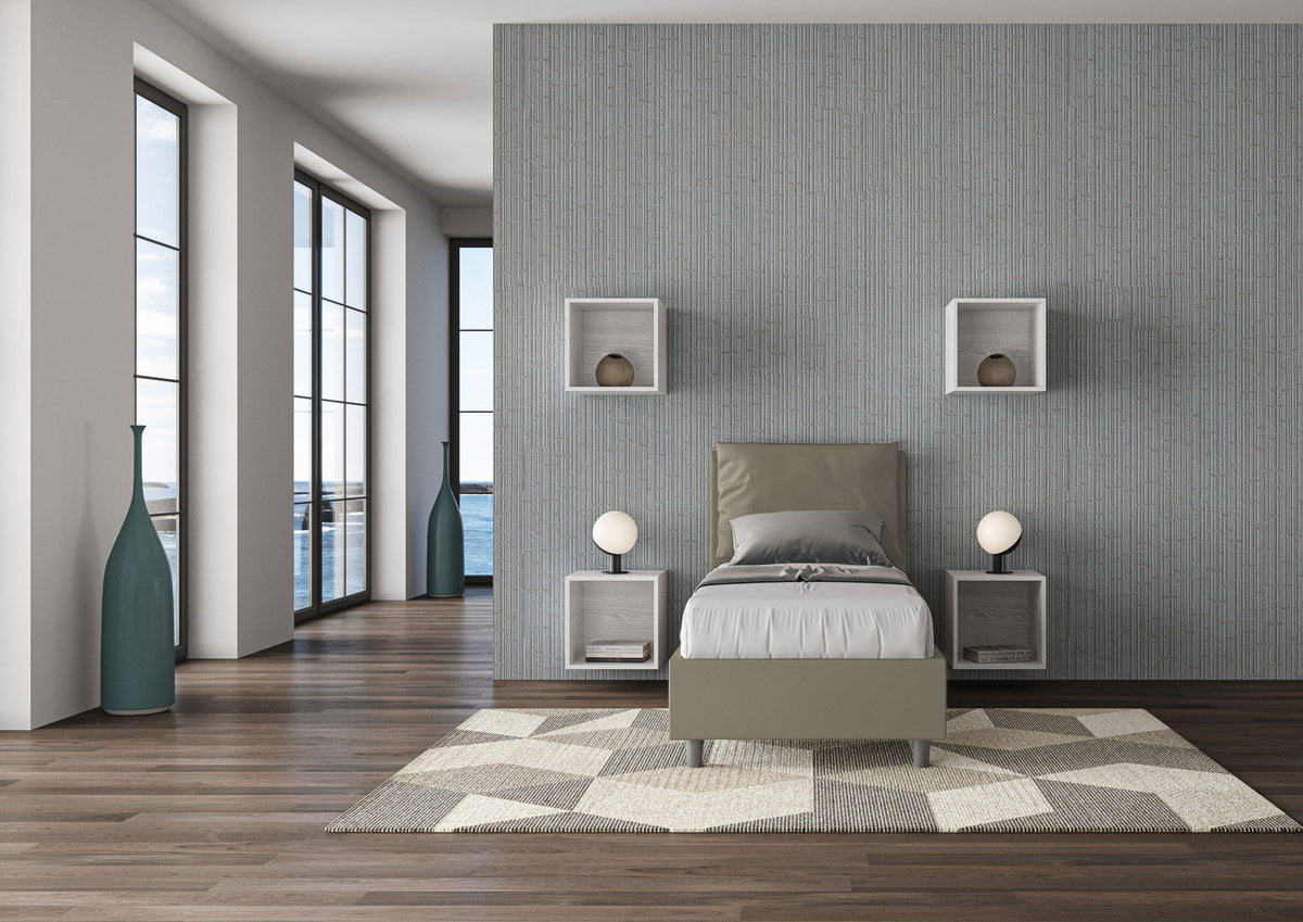 Letto singolo Antea grigio tortora 80x190 con testata imbottita, posizionato in una stanza luminosa con vista mare e pavimento in legno.