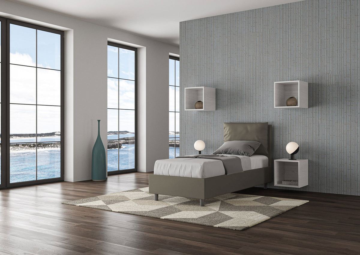 Letto singolo Antea grigio tortora in similpelle con contenitore, ideale per camere moderne con ampie finestre e luce naturale.