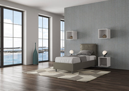 Letto singolo Antea grigio tortora in similpelle con contenitore, ideale per camere moderne con ampie finestre e luce naturale.