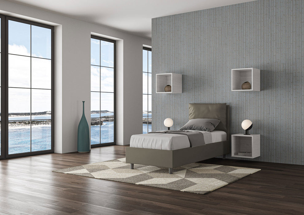 Letto singolo Antea grigio in similpelle con testata imbottita, ambientato in una stanza luminosa con vista panoramica.