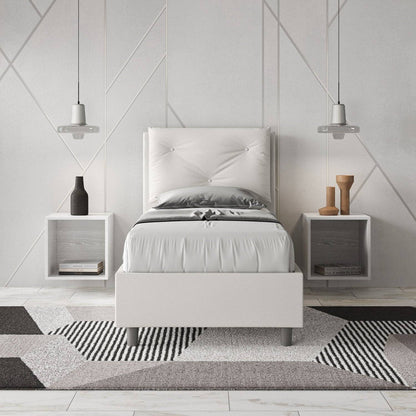 Letto singolo 80x200 in similpelle bianca con testiera trapuntata, inserito in una camera moderna con comodini sospesi.