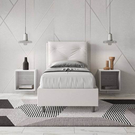 Letto singolo 80x200 in similpelle bianca con testiera trapuntata, inserito in una camera moderna con comodini sospesi.