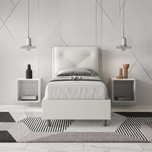 Letto singolo Appia bianco in similpelle con testiera imbottita, inserito in camera moderna con comodini sospesi e tappeto geometrico