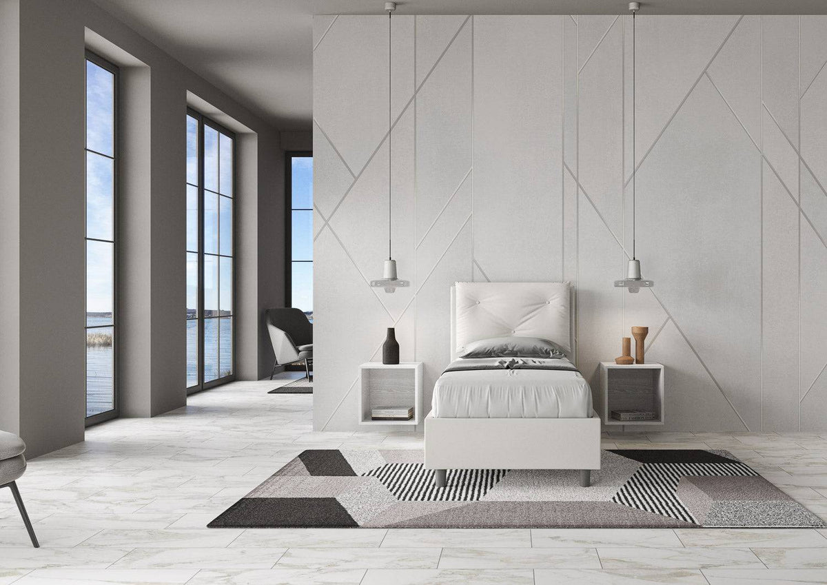 Camera moderna con letto singolo 80x200 in similpelle bianca, ampie finestre e decorazioni geometriche.