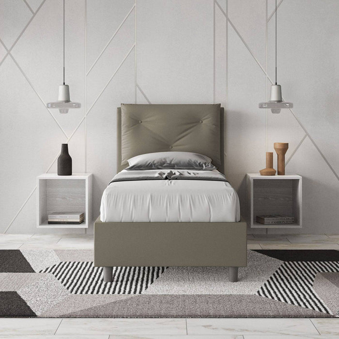 Letto singolo 80x200 in similpelle grigia con testiera trapuntata, inserito in una camera moderna con decorazioni geometriche.