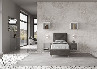 Letto singolo Appia grigio antracite 80x190 con struttura imbottita, posizionato in una camera luminosa con arredi sospesi e vista esterna.