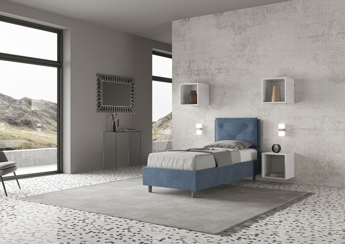 Letto singolo Appia blu navy con testata imbottita, posizionato in una stanza luminosa e moderna con ampie vetrate e arredi minimal.