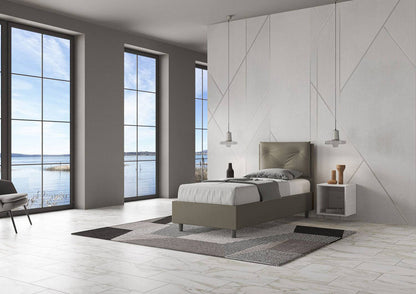 Letto singolo 80x200 in similpelle grigia con testiera trapuntata, posizionato in una stanza luminosa con vista panoramica.