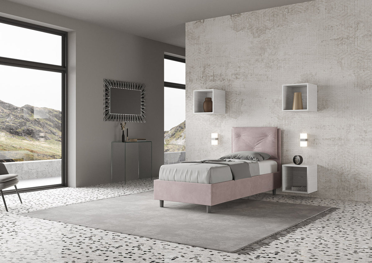Letto singolo Appia rosa cipria con struttura imbottita e testata alta, posizionato in una camera luminosa e moderna con vista panoramica.