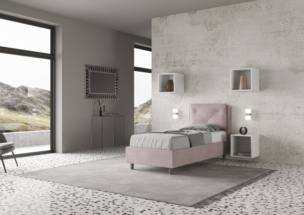 Letto singolo Appia rosa cipria con struttura imbottita e testata alta, posizionato in una camera luminosa e moderna con vista panoramica.