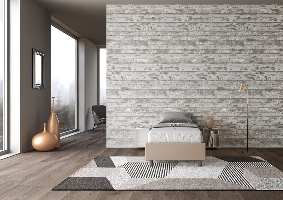 Letto singolo Azelia in similpelle beige con rete, ambientato in camera luminosa con tappeto geometrico e pareti chiare.