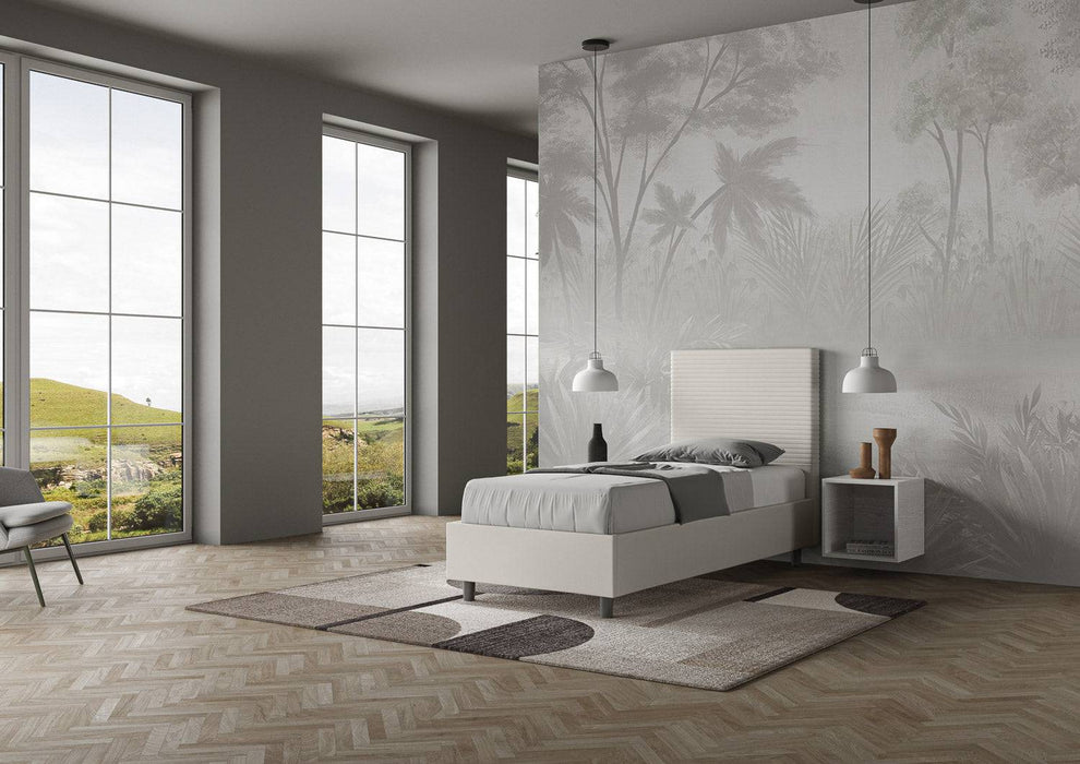 Letto singolo Focus bianco con contenitore e testiera imbottita, posizionato in camera moderna con parquet e vista collinare.