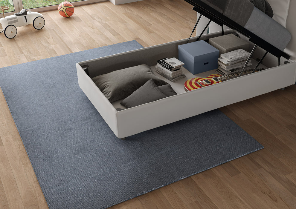Contenitore letto singolo Adele bianco in similpelle, ampio spazio salvaspazio per cuscini, libri e giochi, ideale per camere funzionali.