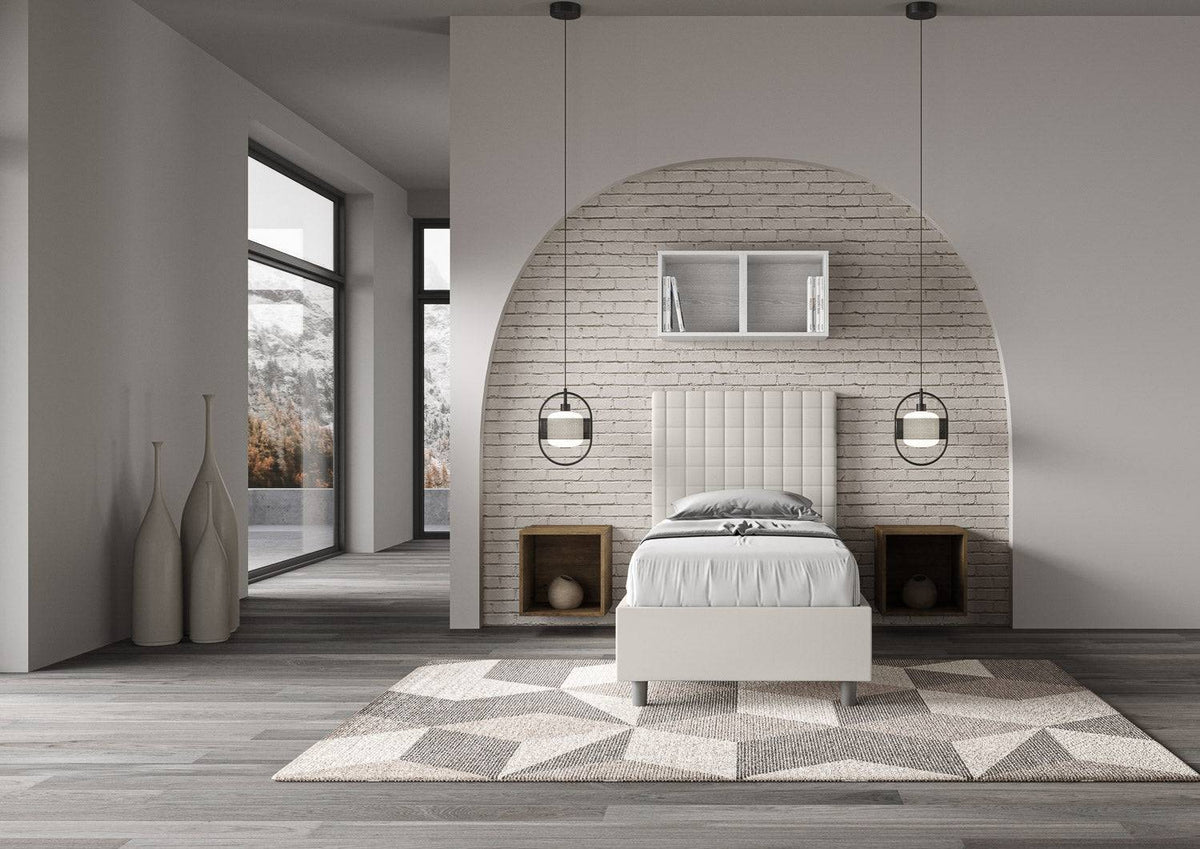 Letto singolo imbottito similpelle Sunny bianco in camera luminosa con design contemporaneo e dettagli architettonici curvi.