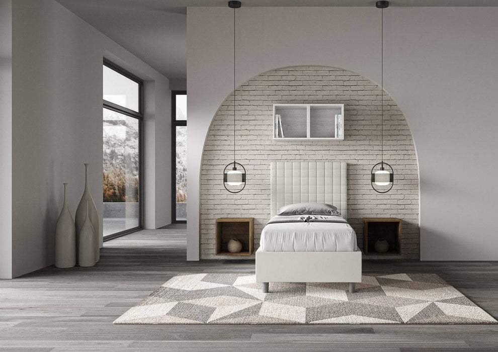 Letto singolo contenitore imbottito similpelle Sunny bianco in camera dal design contemporaneo con tappeto geometrico e luce naturale.