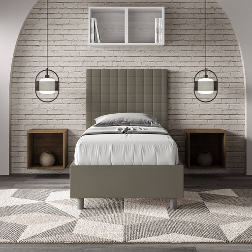 Letto singolo contenitore imbottito similpelle Sunny grigio tortora in ambiente moderno con parete in mattoni e arredi minimal.