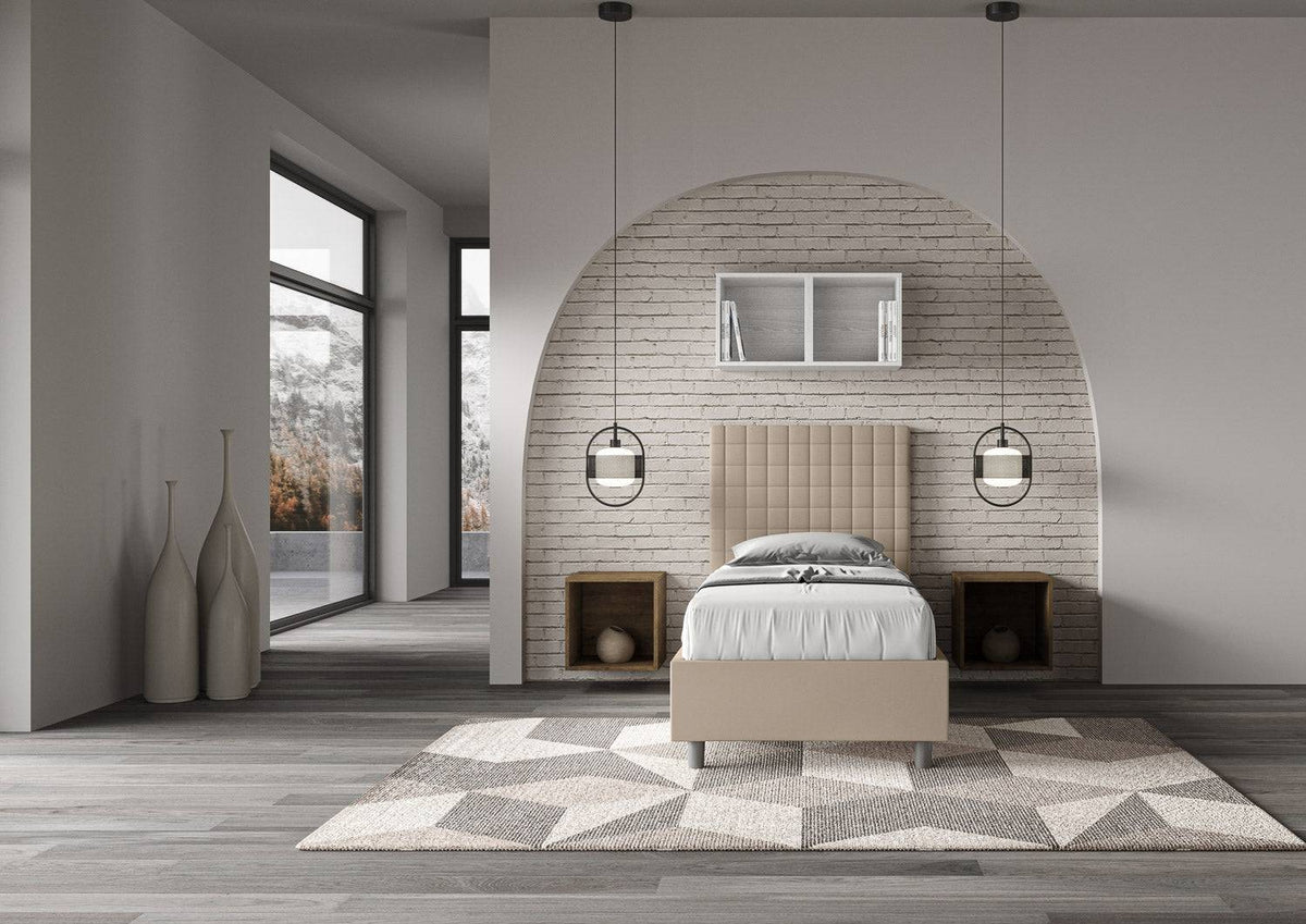 Letto singolo imbottito similpelle Sunny beige in ambiente luminoso e moderno con dettagli architettonici curvi e stile minimal.