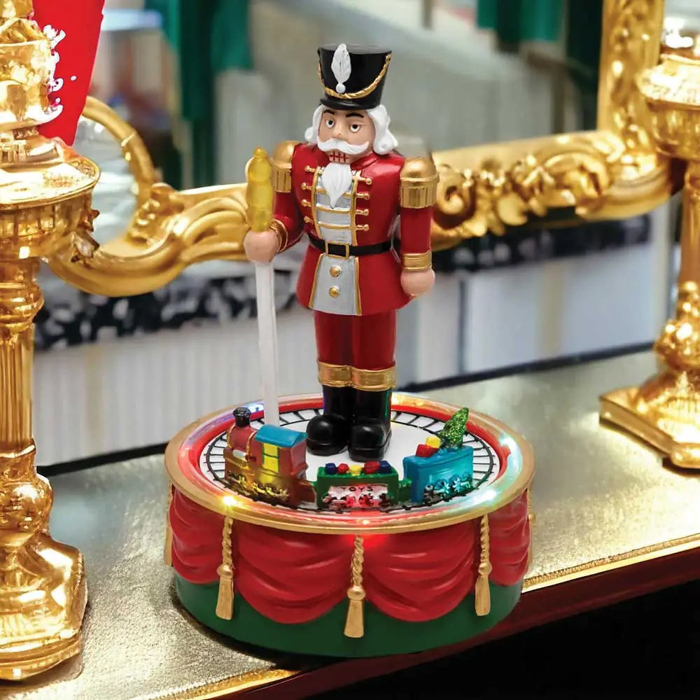Soldato Schiaccianoci natalizio con trenino rotante e luci LED, figura decorativa in resina rossa, nero e oro, con base decorata a festa