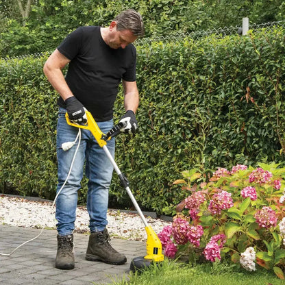 Uomo che utilizza il tagliabordi elettrico Powerplus 350W con guanti, in giardino con cespugli e fiori, per potatura e rifinitura del prato