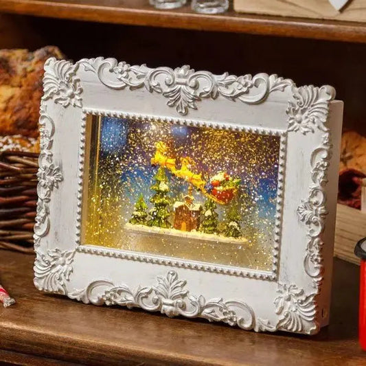 Quadro led natalizio con glitter e acqua in movimento 27x21 cm, cornice bianca decorativa con scena di Babbo Natale in volo, Hobby Shop Solution