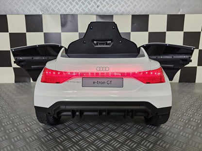 Auto elettrica per bambini Audi E-Tron bianca con portiere aperte, dettagli di design realistici e interni con volante e strumentazione digitale