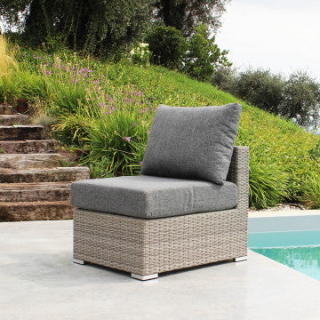 Poltrona Copacabana in wicker grigio con struttura in alluminio e cuscini da 12 cm, posizionata vicino a una piscina in un ambiente esterno elegante.