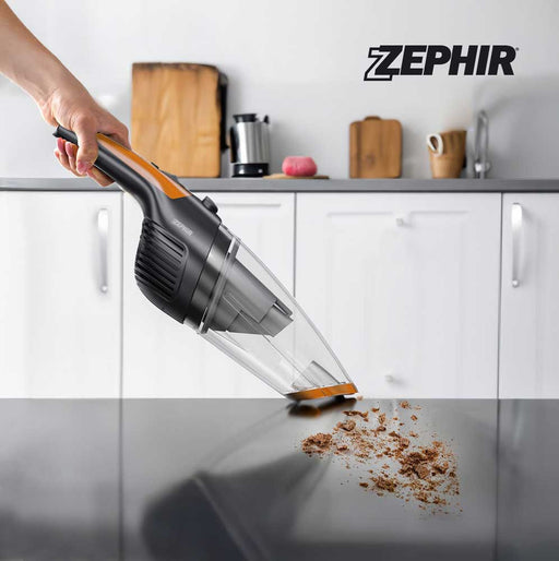 Aspiratutto portatile Zephir con manico ergonomico, in uso su superficie di cucina bianca, con polvere e detriti visibili sotto.