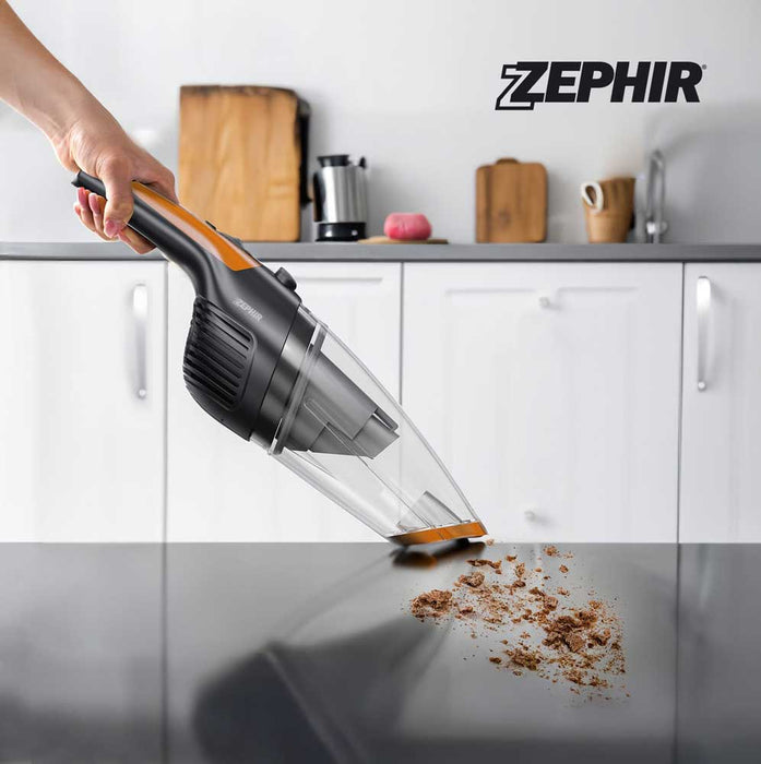 Aspiratutto portatile Zephir con manico ergonomico, in uso su superficie di cucina bianca, con polvere e detriti visibili sotto.