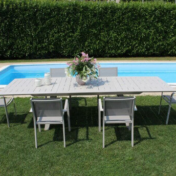 Tavolo Zante allungabile grigio chiaro in giardino con sedie coordinate, ideale per pranzi all’aperto.