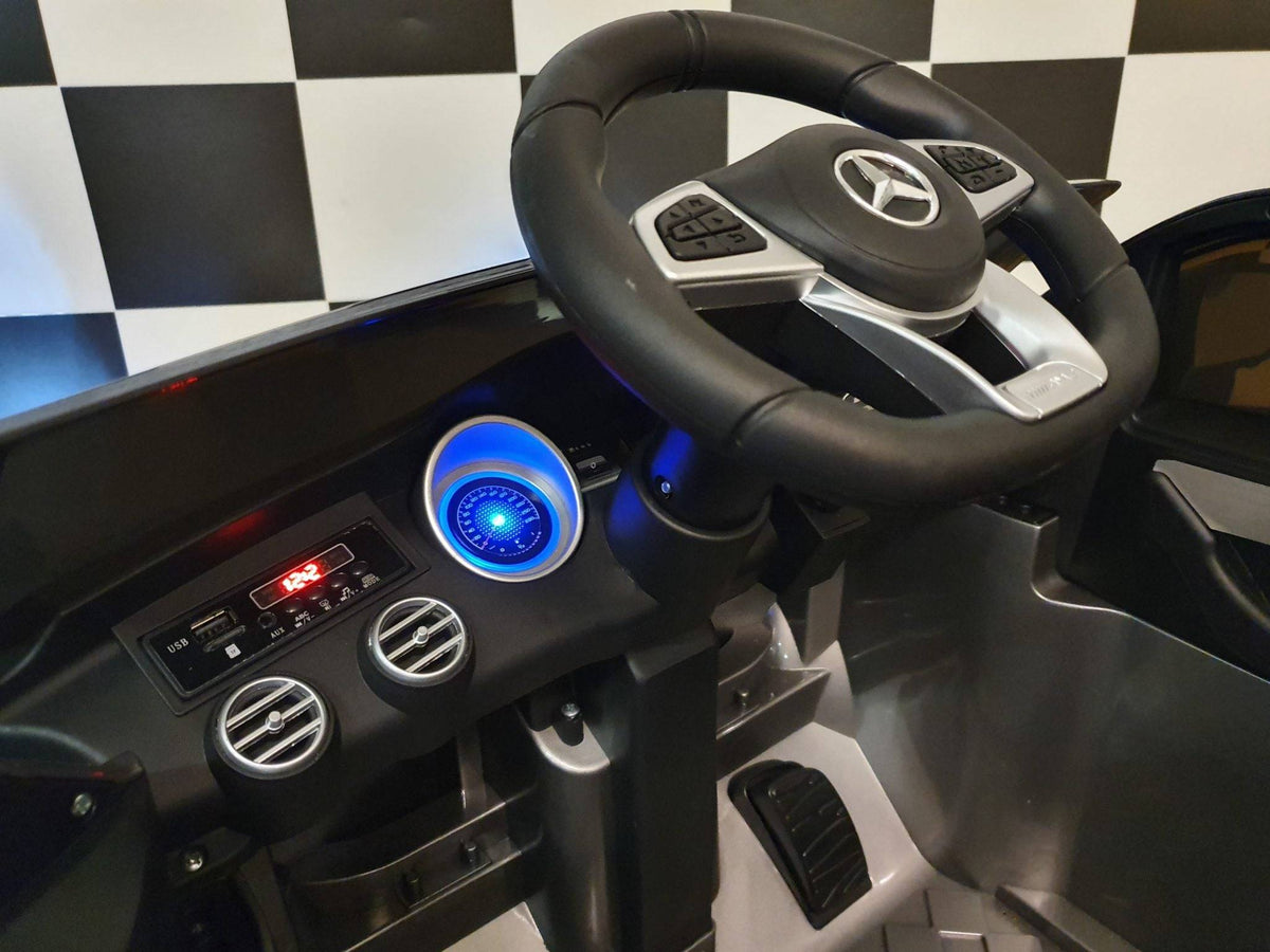 Dettaglio del volante dell'auto elettrica per bambini Mercedes GLC 63 AMG, con logo Mercedes e comandi integrati.