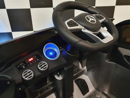Dettaglio del volante dell'auto elettrica per bambini Mercedes GLC 63 AMG, con logo Mercedes e comandi integrati.