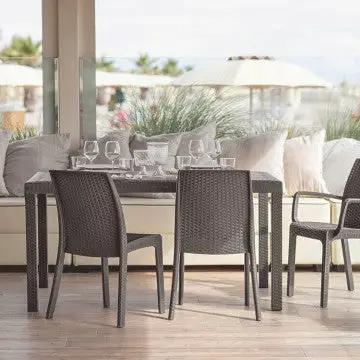 Set di Poltrone Indiana grigie in wicker con tavolo in un ambiente esterno. Ideale per arredare terrazze e giardini.