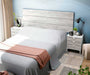 Testiera letto con grande pannello in legno bianco chiaro, abbinata a comodini bianchi con cassetti, in una camera moderna e luminosa.