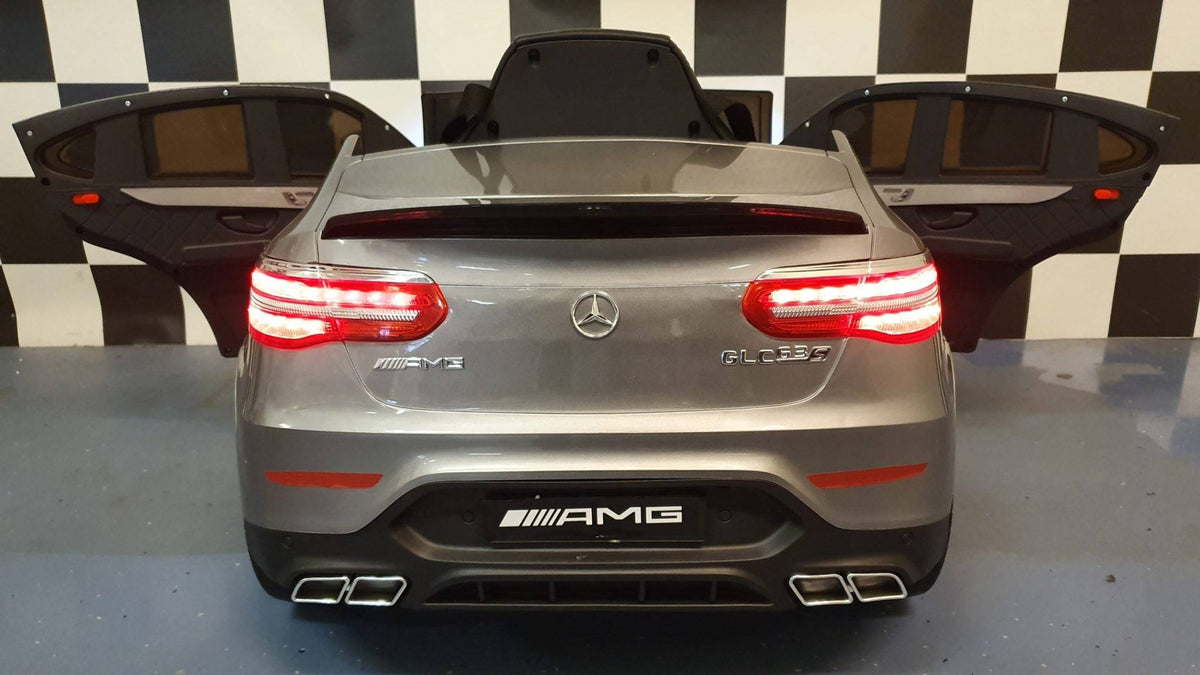 Auto elettrica per bambini Mercedes GLC 63 AMG 12 V in grigio metallizzato, con portiere aperte e dettagli realistici, sedile e volante.