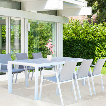 Tavolo Carson 195 x 90 cm con struttura bianca in un ambiente esterno, abbinato a sedie moderne per un design raffinato.
