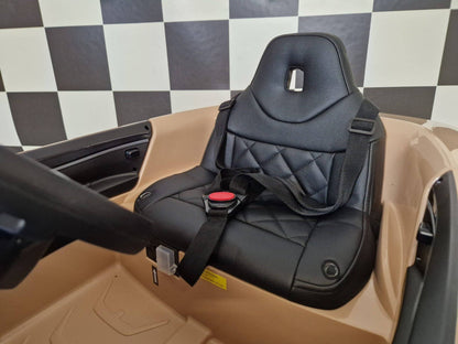 Sedile in pelle nera con imbottitura trapuntata e foro centrale, parte di un'auto elettrica per bambini BMW i4 colore champagne, con cinture di sicurezza