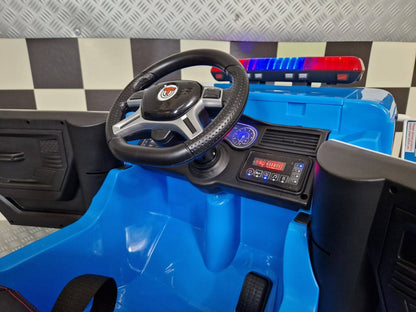 Interno dell'auto della polizia per bambini con volante nero, pannello di controllo con luci e pulsanti, sedile imbottito nero con cinture di sicurezza.