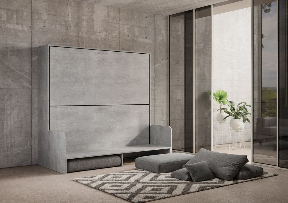 Letto a scomparsa Kando Sofà effetto cemento in fase di apertura, con divano trasformabile e materassi integrati, ideale per spazi multifunzionali.