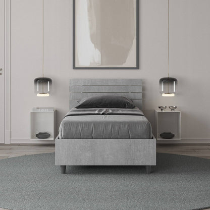 Letto singolo Ankel grigio in una camera moderna, con testiera a doghe e arredamento minimalista e funzionale.