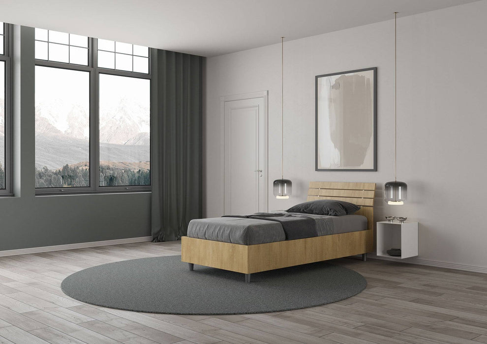 Letto singolo Ankel effetto legno chiaro con contenitore, posizionato in una camera con ampie finestre e vista panoramica.